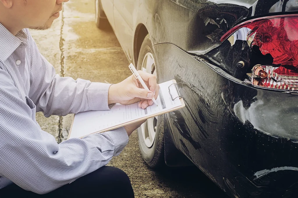 man writing inspection report on paper in front of black car buying inspection in Fairfield Place