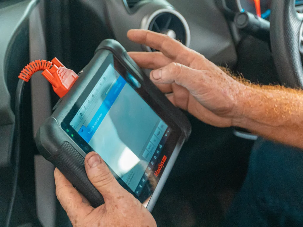 Car inspection mobile service at Cypress Creek Lakes, a technician using a diagnostic tablet inside a car.