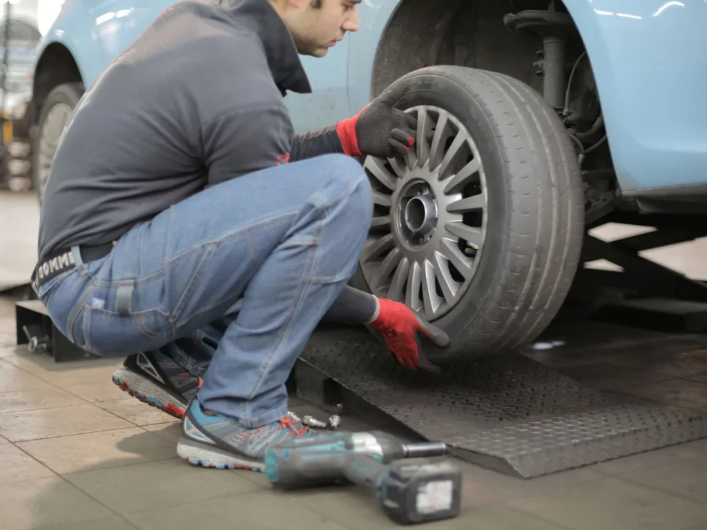 A mechanic performing a mobile auto evaluation in Harvest Bend The Meadow, checking a car's tire.