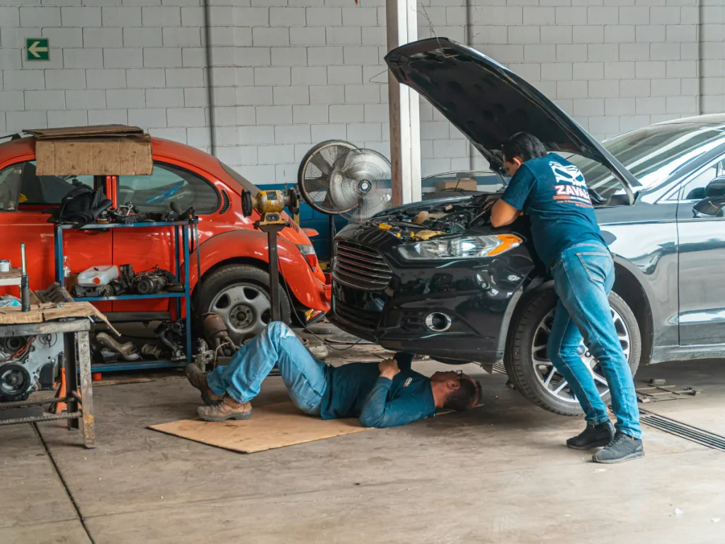 An experienced team of auto technicians performing a detailed inspection on a car, demonstrating professional mobile auto inspection services in Houston.