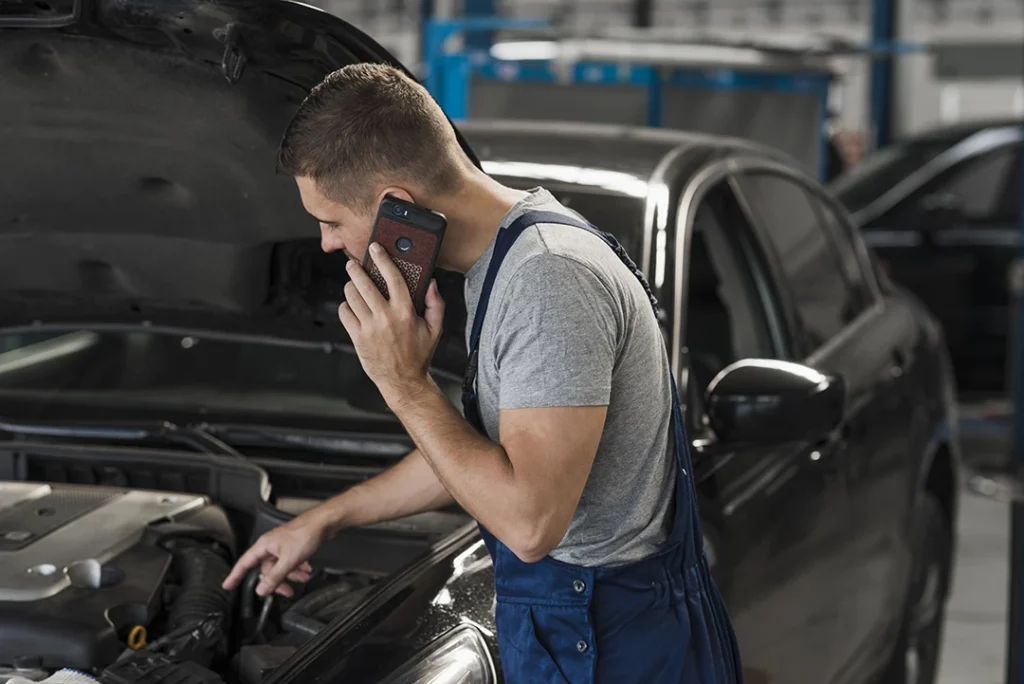 Mechanic checking vehicle holding a phone during mobile re purchase inspection in Houston.