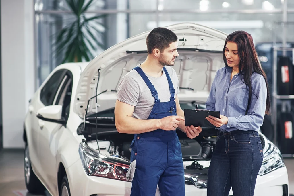 Man mechanic explaining completed mobile used car inspection in Lakes On Eldridge to female customer.