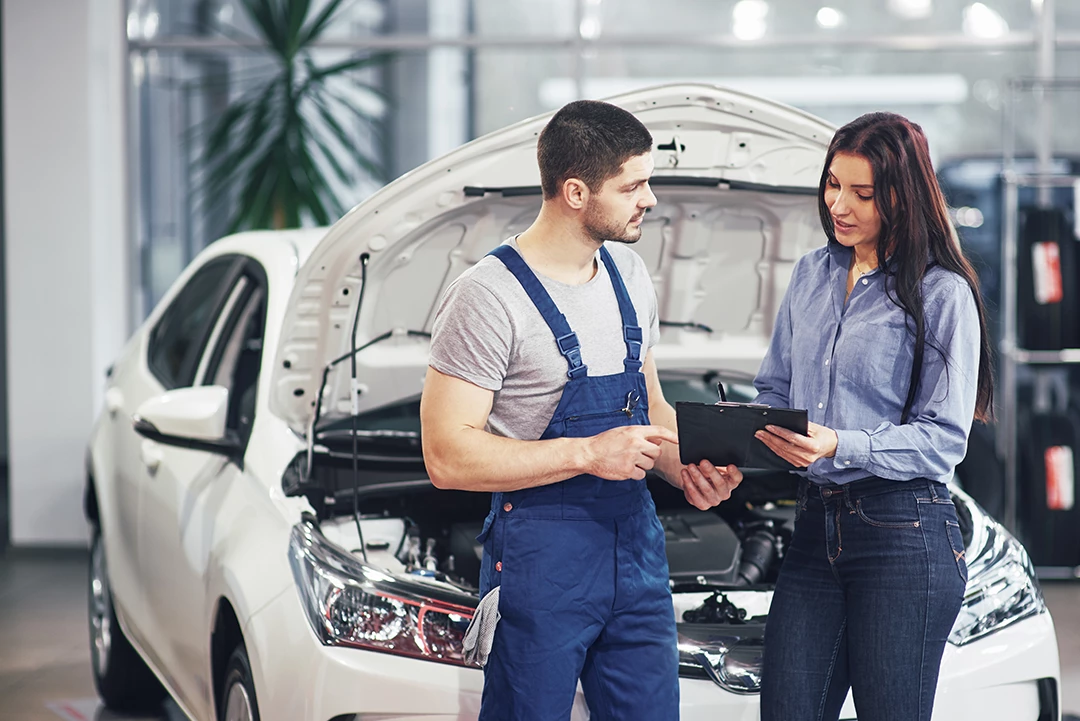Man mechanic explaining completed mobile used car inspection in Lakes On Eldridge to female customer.