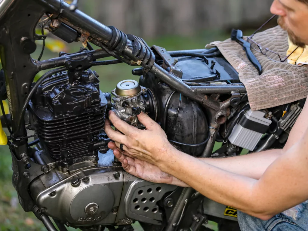 A detailed motorcycle inspection in Houston, with a mechanic handling the carburetor.