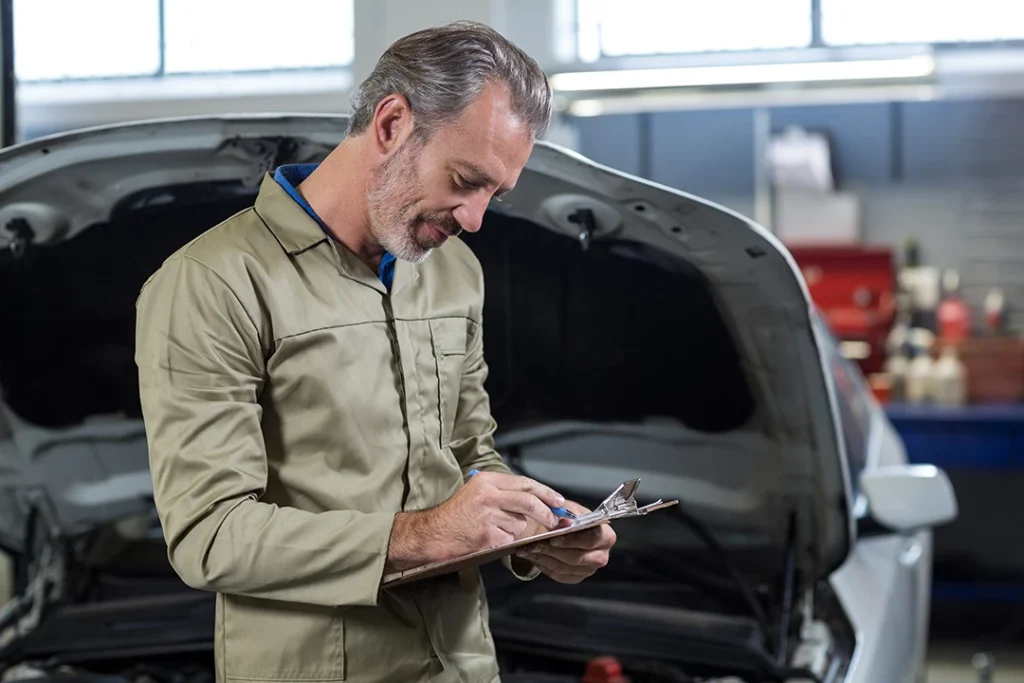 Male auto technician listing his notes for pre purchase inspection houston tasks.