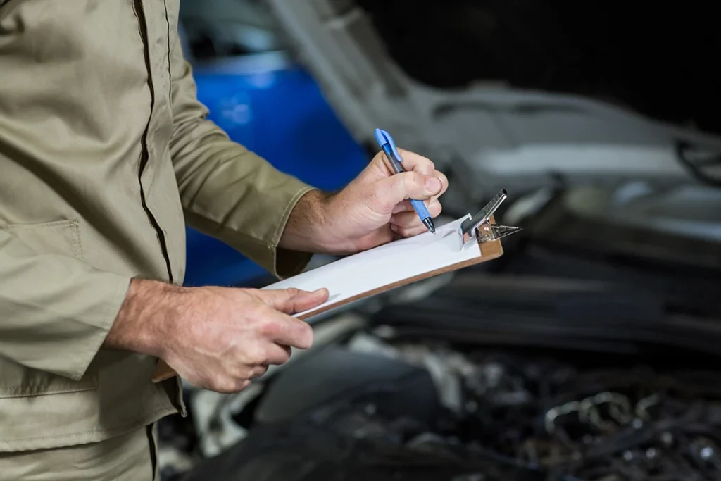 Man writing vehicle inspection before buying notes during pre purchase auto inspection in North Forest