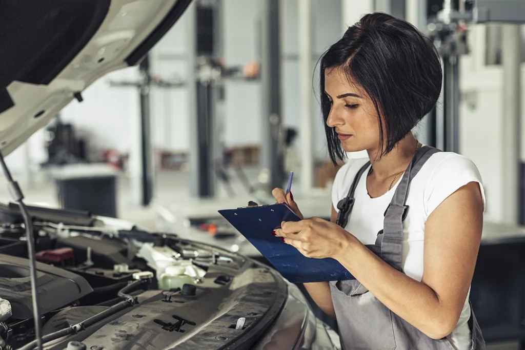 Woman checking engine during a vehicle inspection before purchase Northwest Houston service.