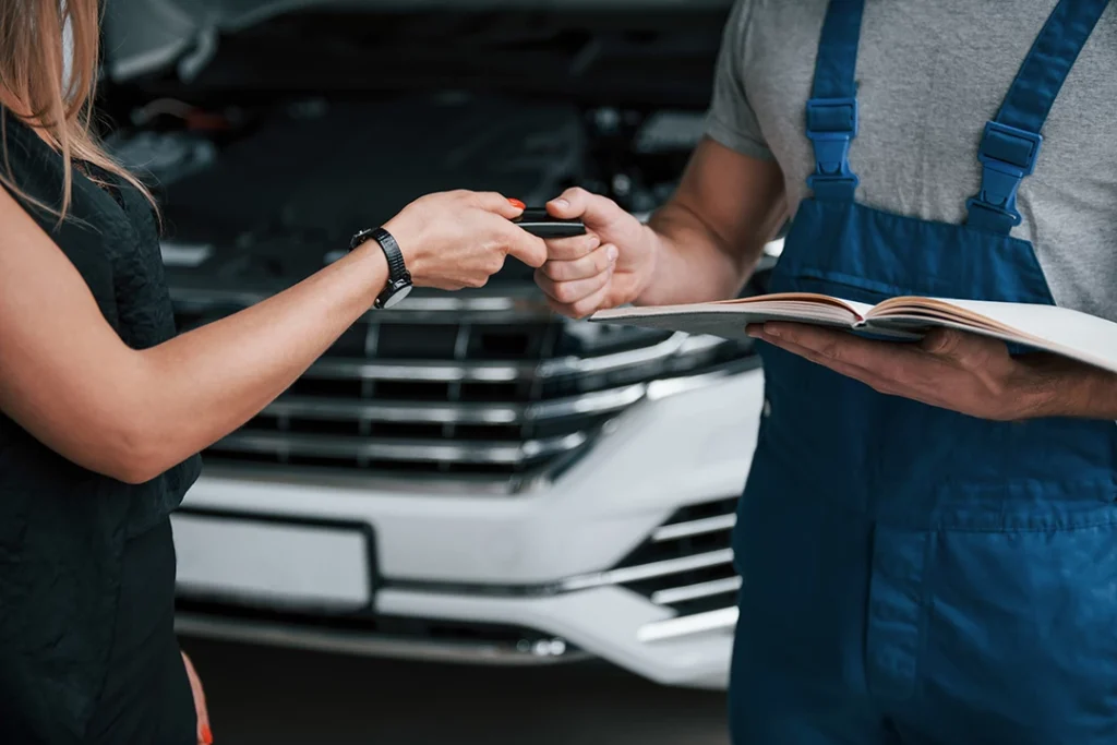 Owner handing car key to inspector during a vehicle inspection service northwest Houston service.