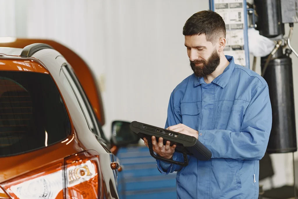 Car mechanic using tablet during Westbranch vehicle inspection before buying to take down notes