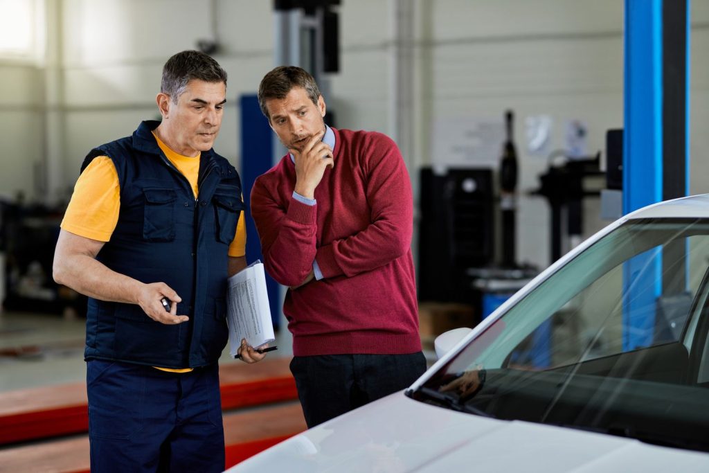 Mechanic reviewing inspection report with client in Houston third party inspection garage.