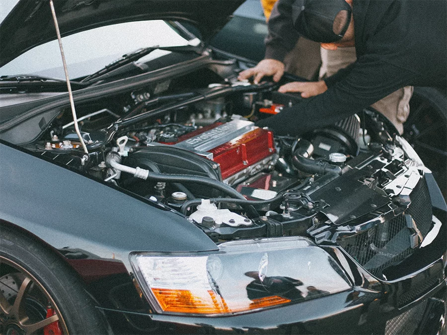 Mechanic inspecting Mitsubishi Lancer Evolution engine for check used car service in Houston under open hood.