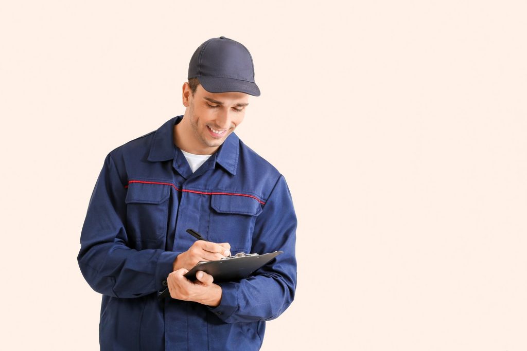 Mechanic in uniform writing on clipboard for used auto inspection Houston service.
