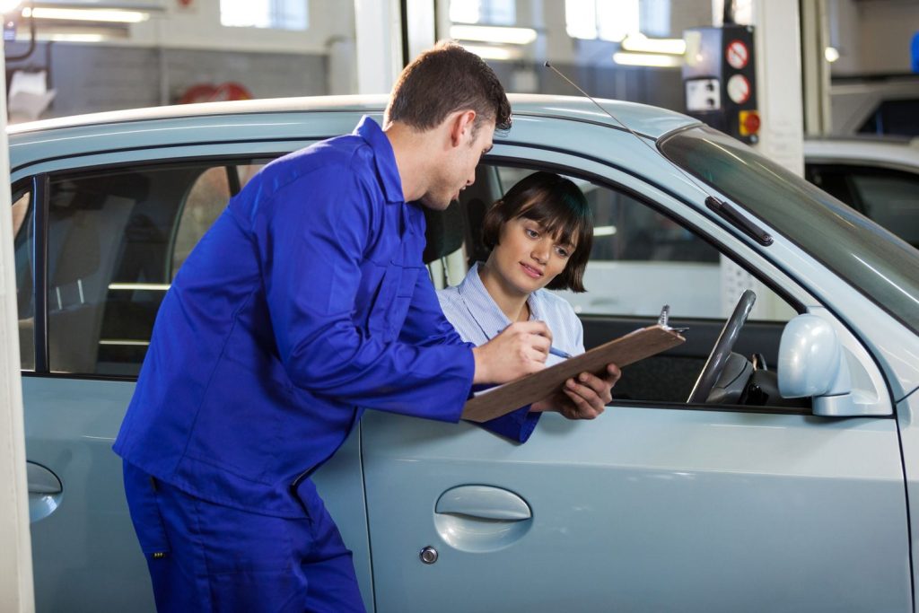 Mechanic reviewing checklist with customer for used car inspection services Houston.