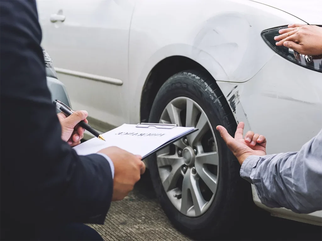 Inspector documenting scratch on used car fender with clipboard during check used car service in Houston.