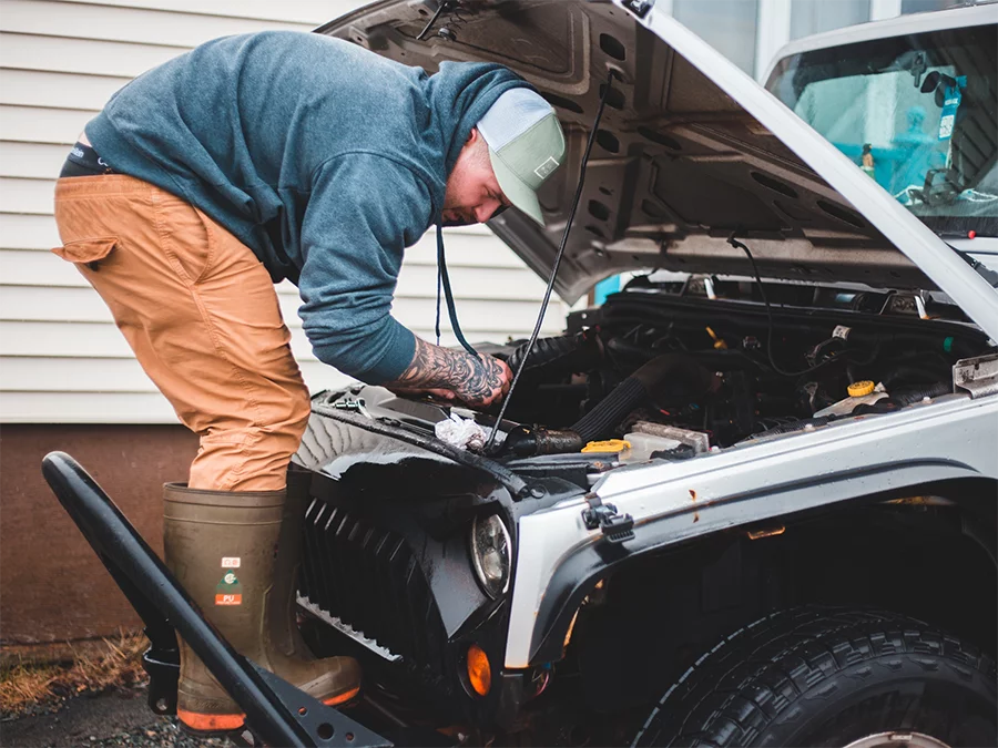 Man inspecting engine of used Jeep Wrangler during check used car service in Houston.