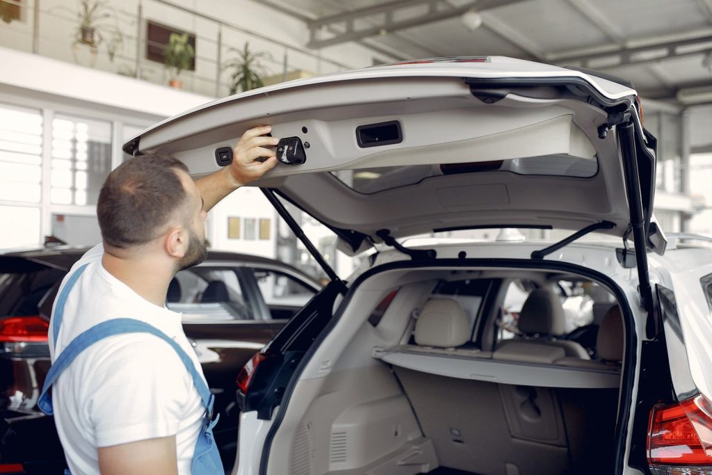 Mechanic inspecting SUV trunk in showroom during pre purchase inspection in Houston.