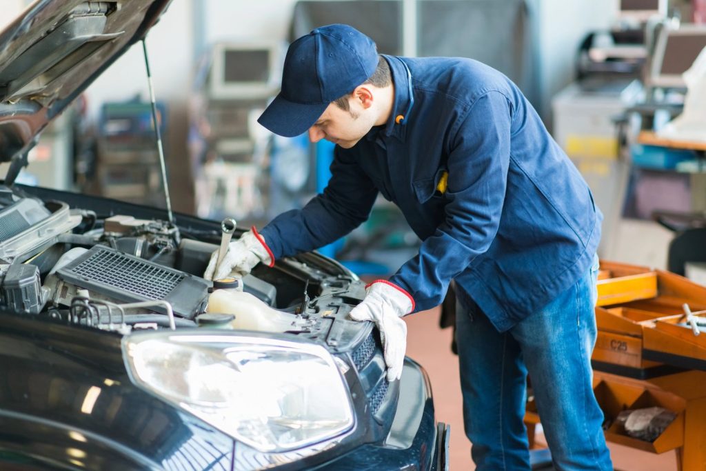 A mechanic performs a pre purchase used car inspection Houston in a garage, checking the engine with tools, ensuring quality service.