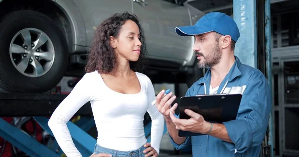 Mechanic discussing pre-purchase used car inspection in Houston with a client next to a lifted vehicle.