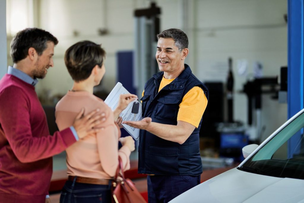 Mechanic handing keys to satisfied couple after Pre Purchase Inspection Houston, confirming reliable vehicle purchase.