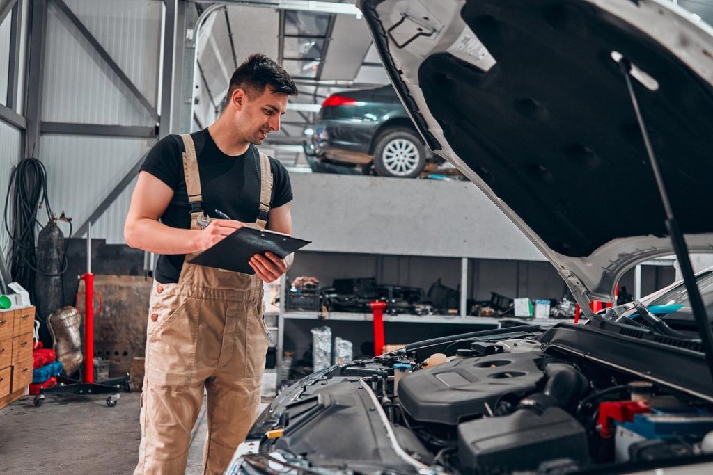 Third party car inspection Houston includes detailed engine checks. Technician records findings in multi-bay auto shop