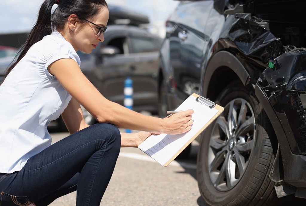 Vehicle damage assessment before you buy car inspection Houston, with inspector reviewing collision repairs and notes.