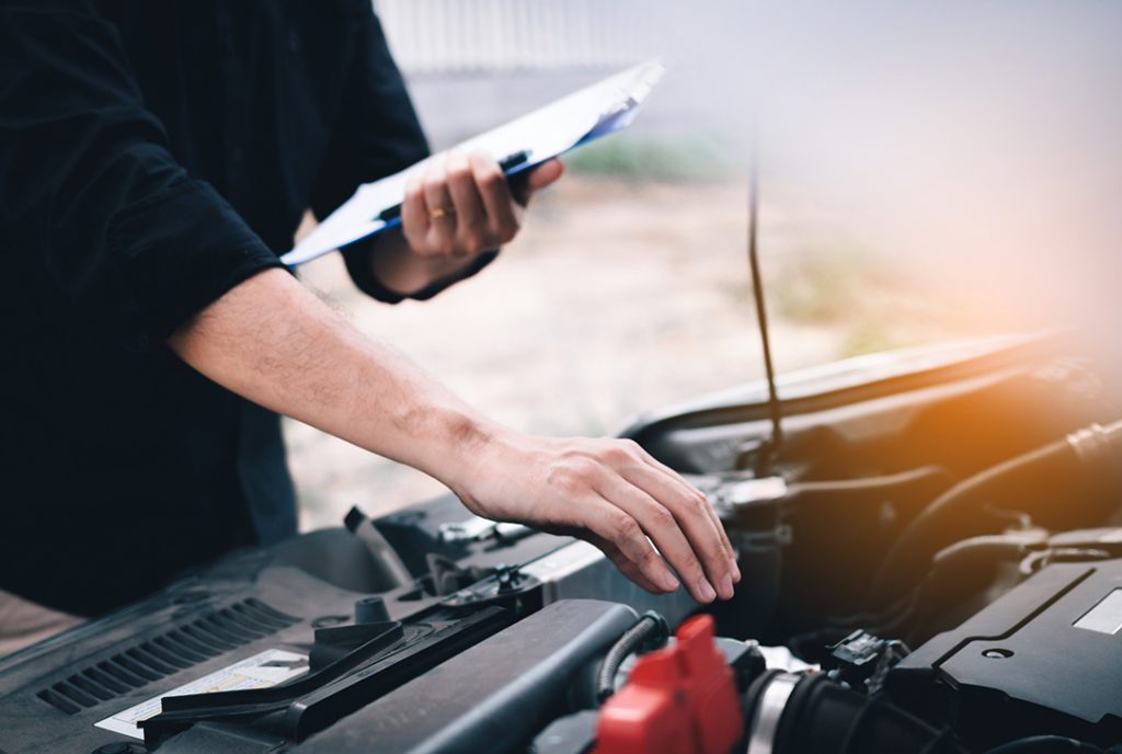 Expert mechanic performing an under-hood inspection as part of a before you buy car inspection Houston service.