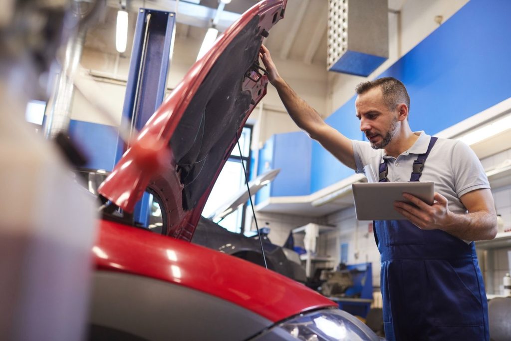 Best car inspection service Houston: Mechanic using a digital tablet for diagnostics and auto repair documentation.