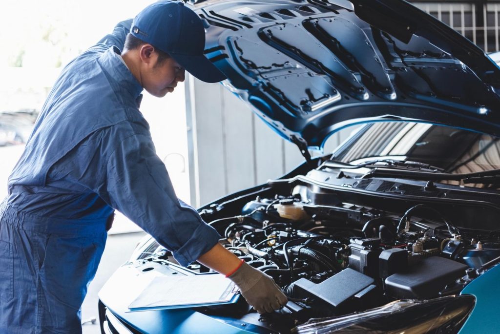 Mechanic checking engine for an official vehicle inspection report. Find the best car inspection service Houston has.