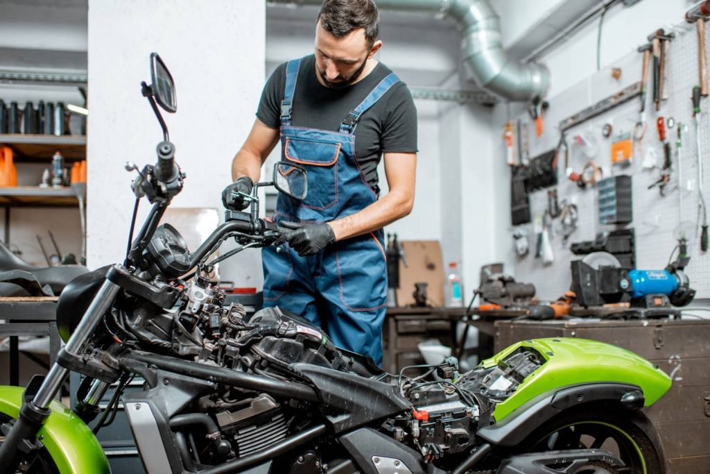 Certified mechanic performing a motorcycle inspection Houston on a green sportbike frame within a diagnostic bay.