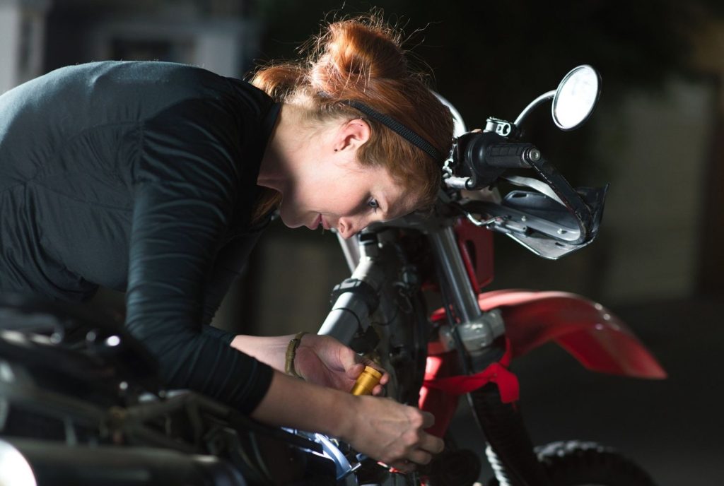 Female mechanic performing a motorcycle inspection Houston residents trust for engine diagnostics and repairs.