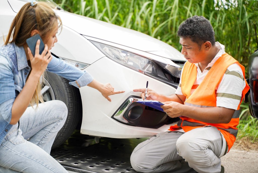 Inspector pointing to bumper damage to check used car service Houston quality during a pre-purchase vehicle evaluation.