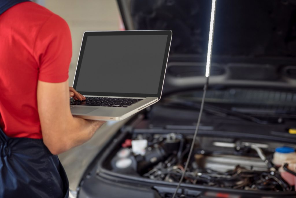 Mechanic performing an independent third party auto inspection using a laptop to run vehicle diagnostic software.