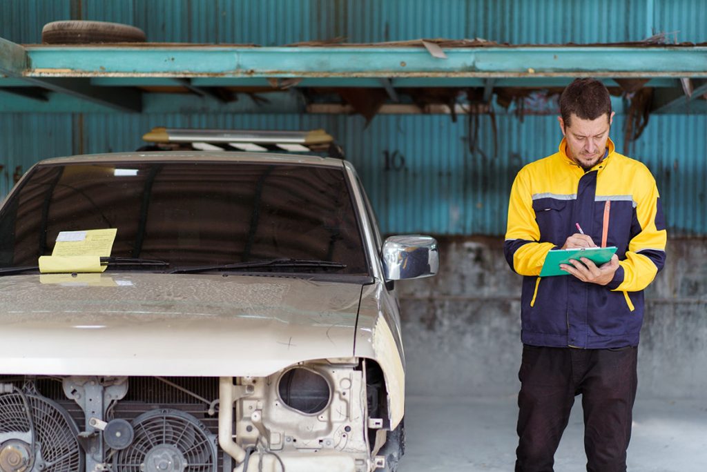 A professional mechanic completes an on-site used car inspection report with a detailed checklist and vehicle.