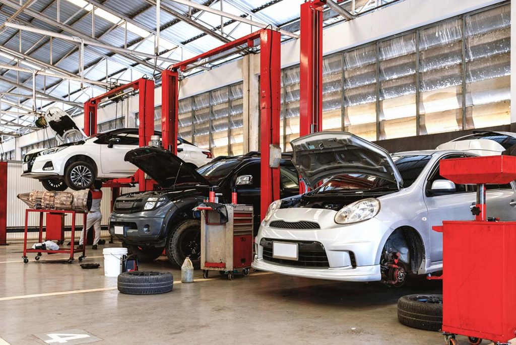 Modern auto service garage providing an on-site used car inspection with vehicles on lifts for full diagnostics.