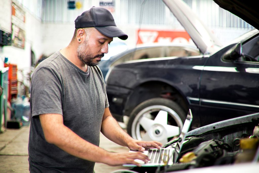 Professional mechanic conducting an independent third party auto inspection on a vehicle inside a repair garage.