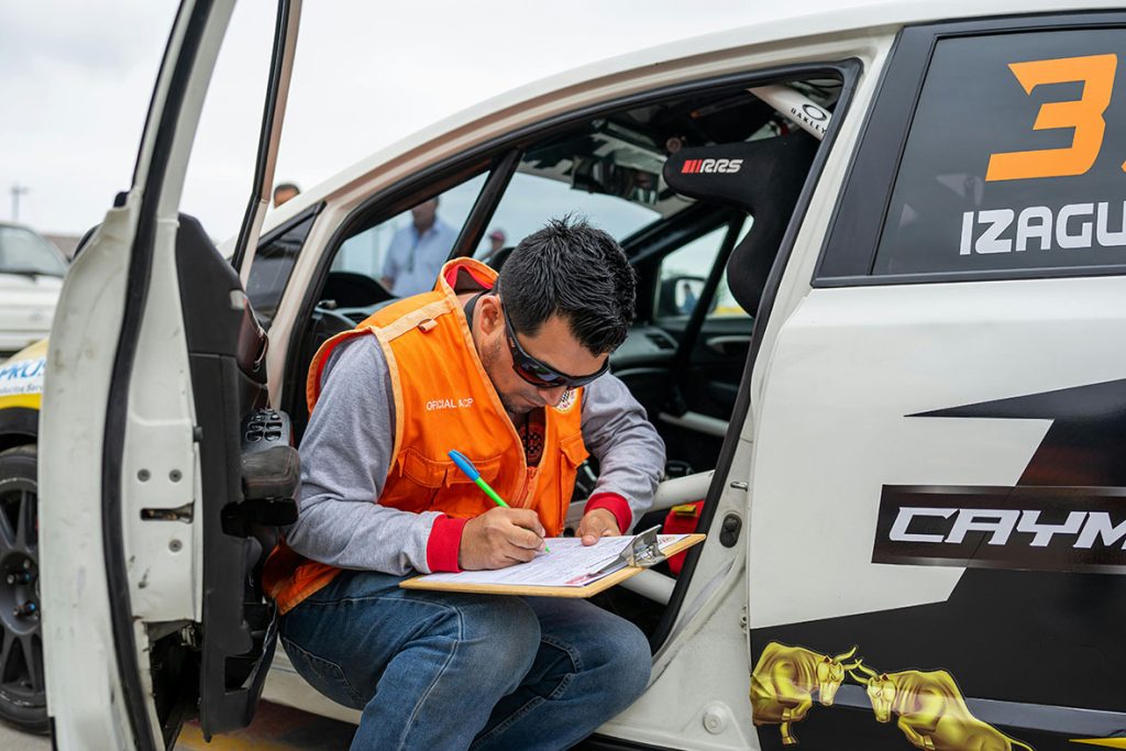 Focused mechanic to check used car before buying filling out a detailed vehicle inspection checklist on a clipboard.