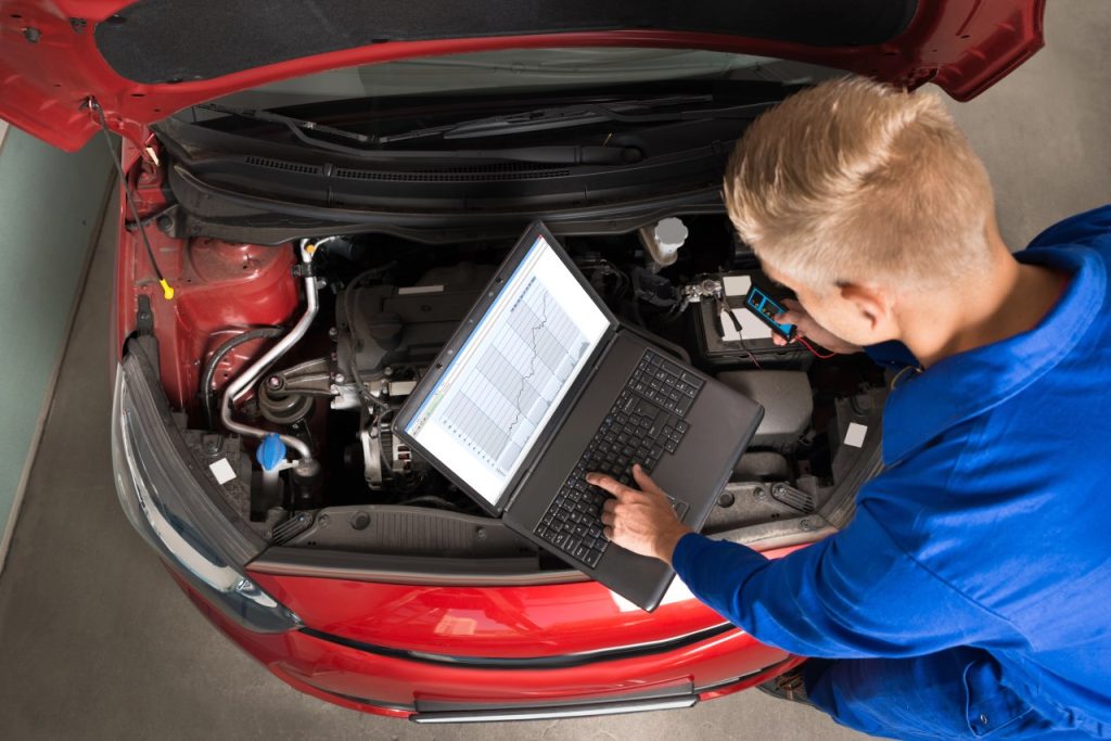 Mechanic using laptop for computer diagnostics at a top-rated vehicle inspection service Houston facility.