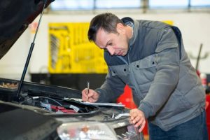Professional mechanic performing a thorough third party inspection Houston on a car engine with a detailed checklist.