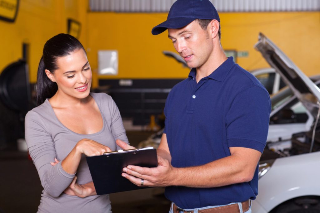 Professional mechanic and client reviewing a detailed third party inspection document at a local service center.