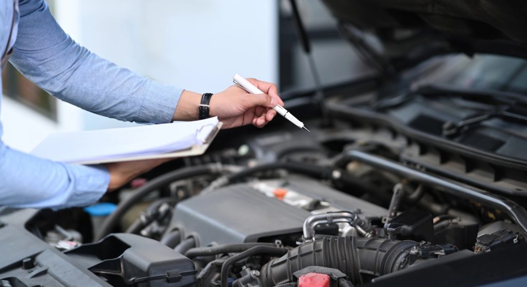 Technician conducting a detailed engine diagnostic as part of a professional certified pre owned car inspection service.