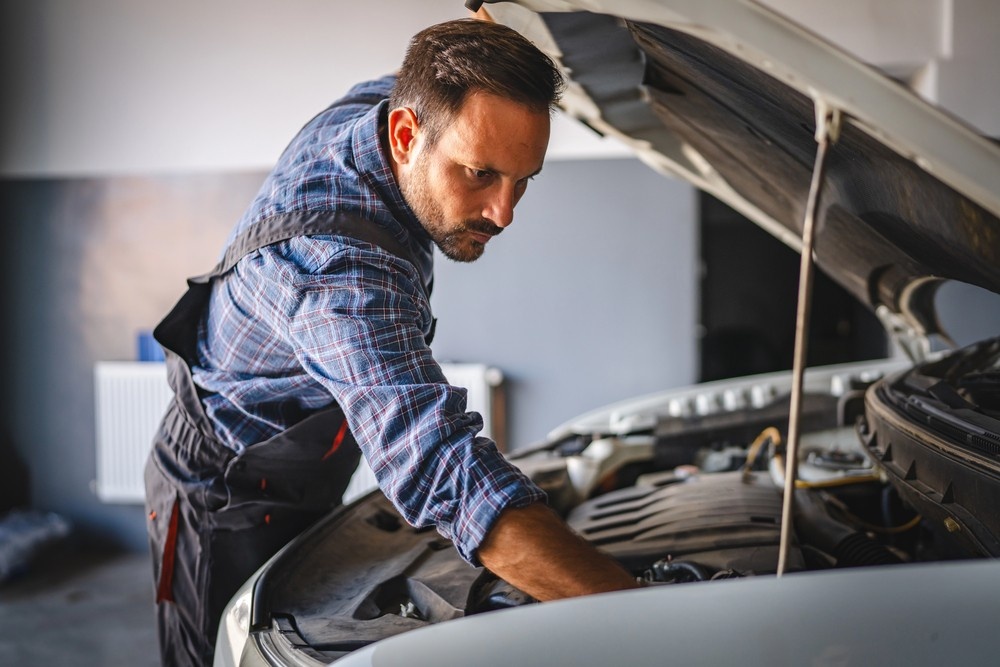 Expert mechanic inspecting a car engine under the hood, a crucial step for third party inspection Houston services.