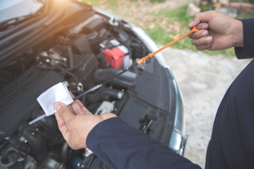 Close up of a dipstick during an independent used car inspection to check engine oil level and fluid quality.