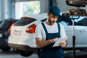 Mechanic in blue overalls uses a tablet for digital reporting during a professional third party inspection Houston.