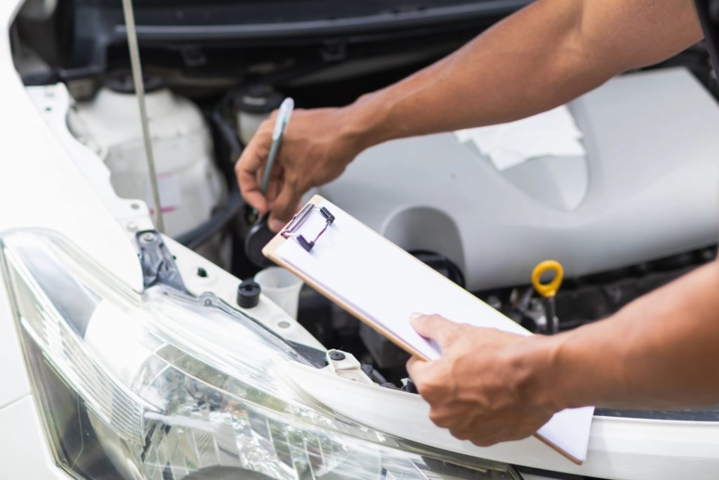 Mechanic checking engine fluid levels during a pre purchase used car inspection to ensure the vehicle is in top shape.