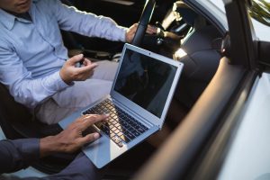 Skilled mechanic to check used car before buying while performing an onboard computer diagnostic in the car interior.