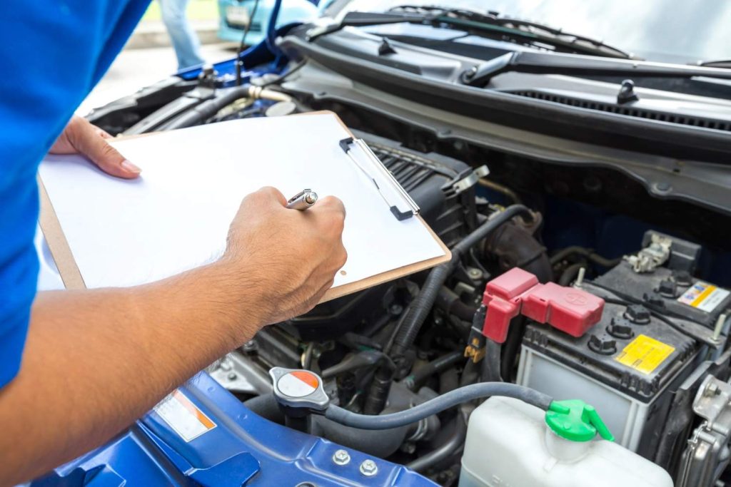 Certified mobile mechanic used car inspection checking the vehicle battery and electrical system terminals. 