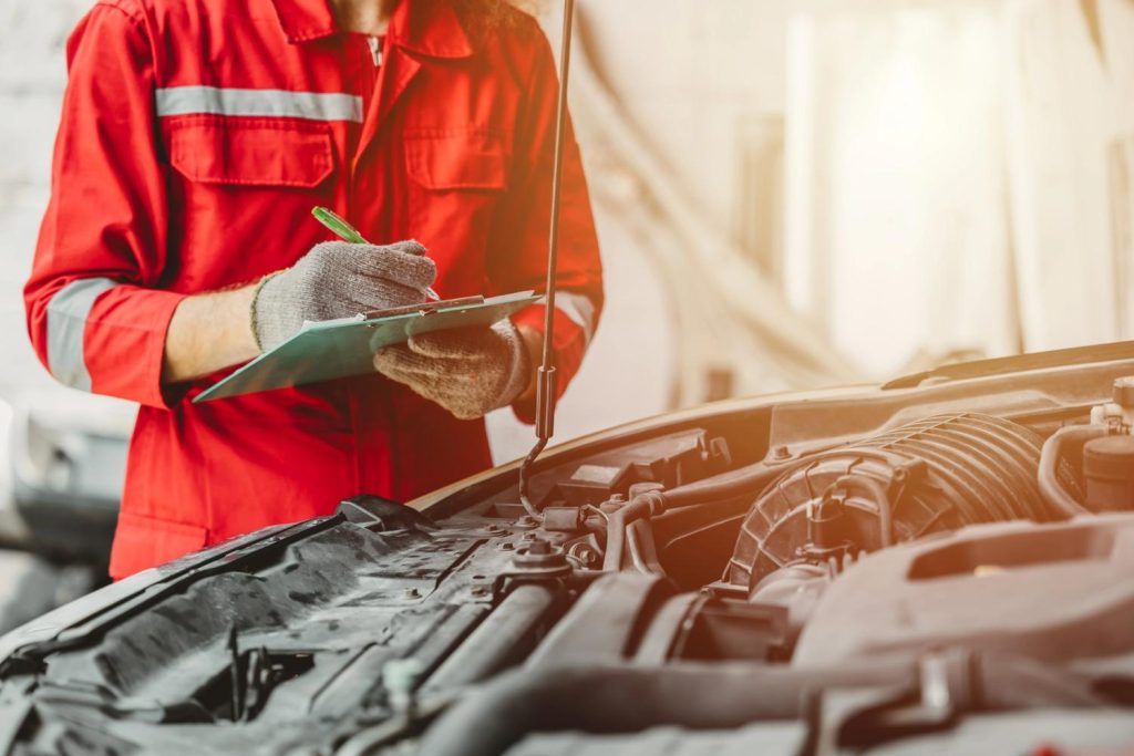 Mechanic performing a mobile third party car inspection service by running a detailed engine bay diagnostic check. 