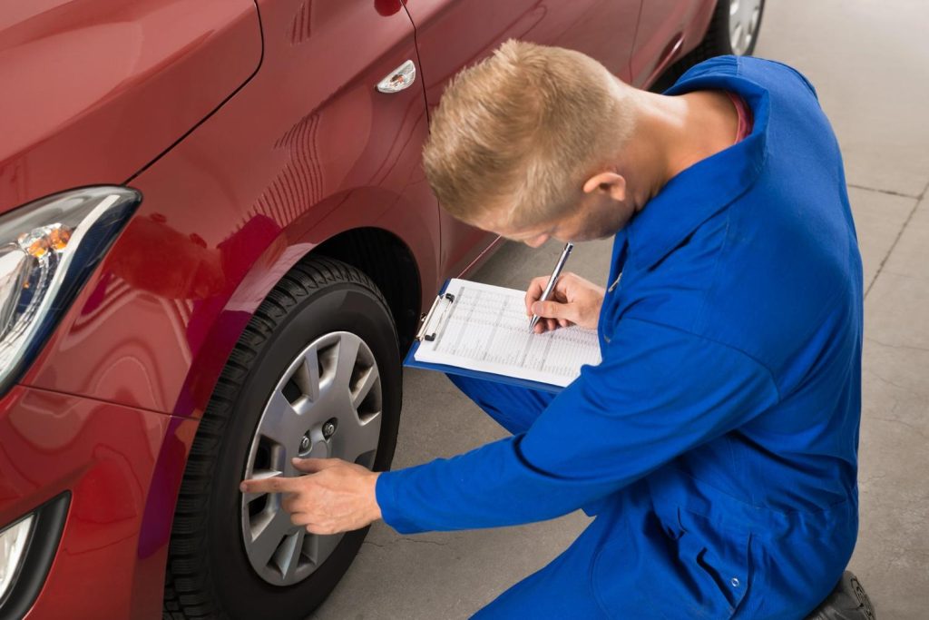 Professional technician providing a mobile third party car inspection service with a full tire and wheel examination. 
