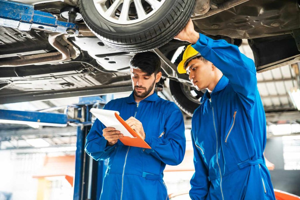 Experts performing a mobile third party car inspection service by checking the undercarriage on a professional lift.