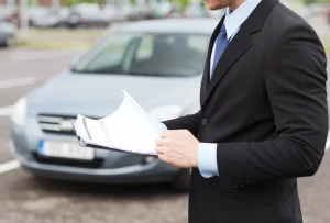 An appraiser reviewing paperwork for a comprehensive pre purchase auto inspection service on a silver vehicle.